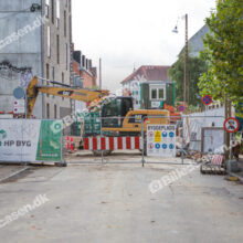 Byggeplads og vejarbejde med stor gravemaskine og henvisning til køretøjer og forgængere