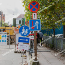 Byggeplads og vejarbejde med stor gravemaskine og henvisning til køretøjer og forgængere